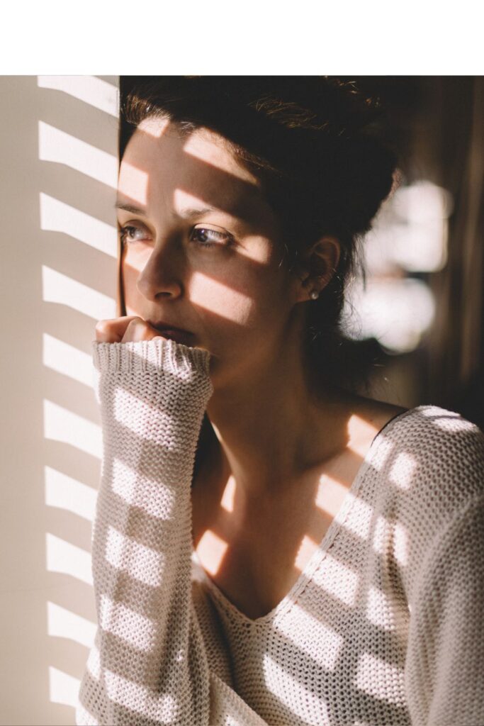 Frau schaut nachdenklich aus dem Fenster – Bild für mentale Erschöpfung und Überlastung im Alltag vieler Mütter